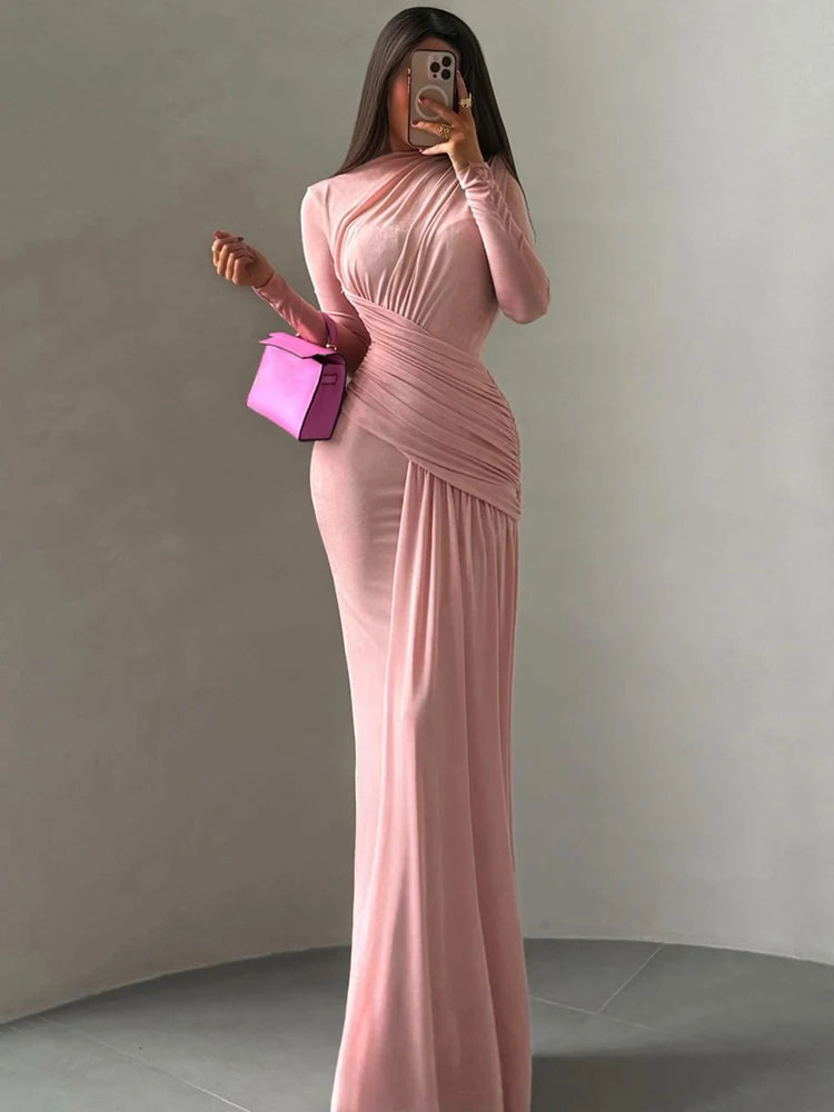 Woman in a pink evening gown holding a pink clutch against a plain background