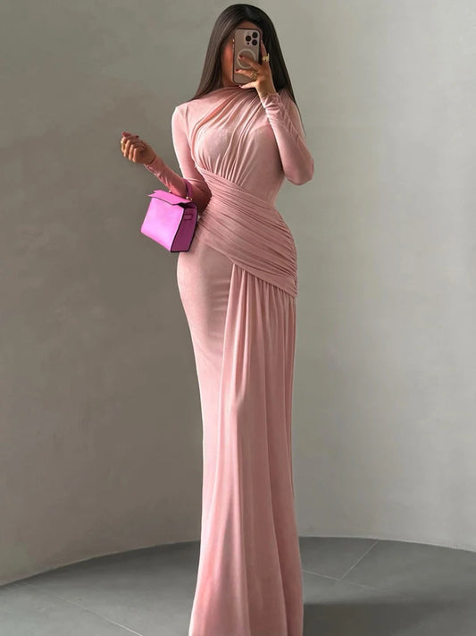 Woman in a pink evening gown holding a pink clutch against a plain background
